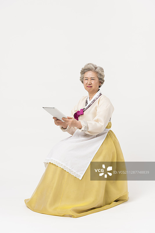 一名身穿韩服、系着围裙、手拿平板电脑的高级女性的照片图片素材