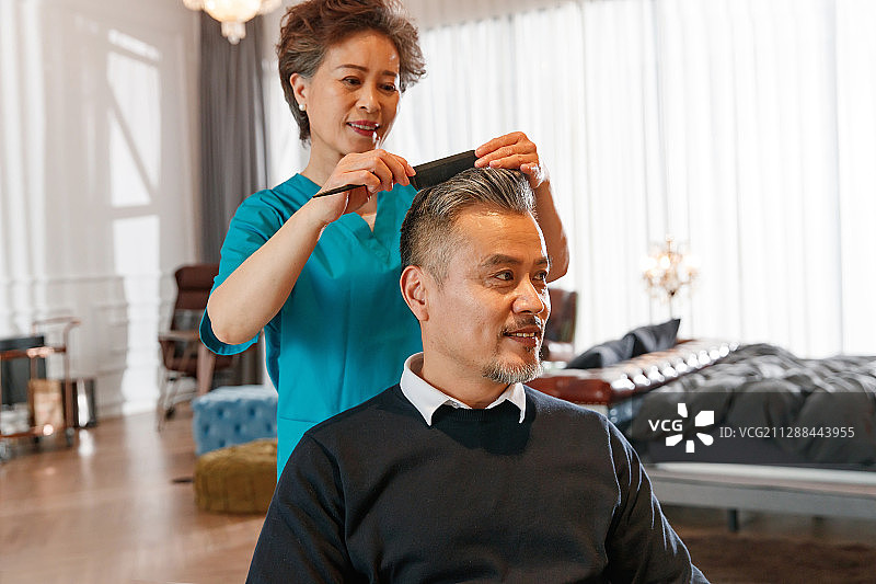 护工给坐轮椅的中年男士梳理头发图片素材