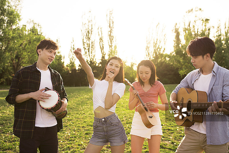 年轻朋友在户外草地唱歌演奏音乐图片素材