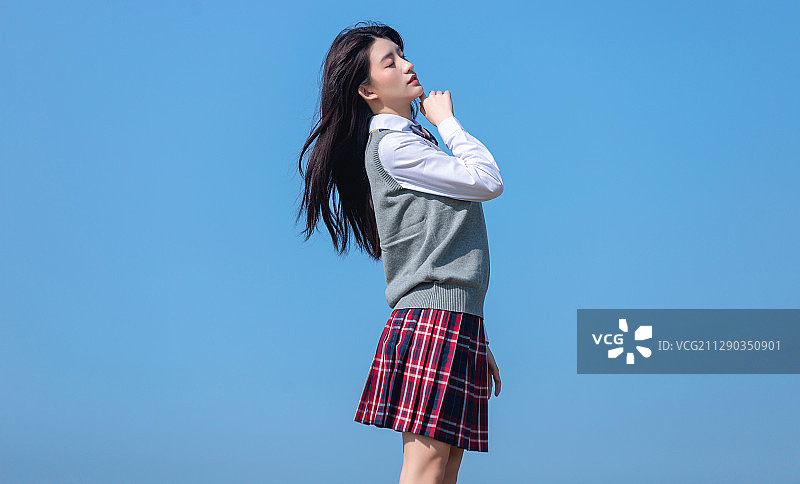 蓝色天空背景下的亚洲女学生图片素材