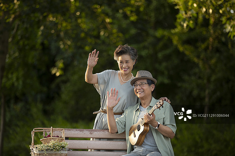 老年夫妻在公园长椅上打招呼肖像图片素材