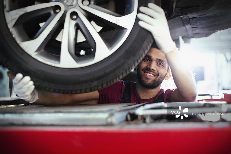 肖像自信，微笑的男性技工在汽车修理店下工作图片素材