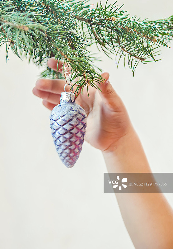 一个人的手在圣诞树上挂着白色的装饰品图片素材