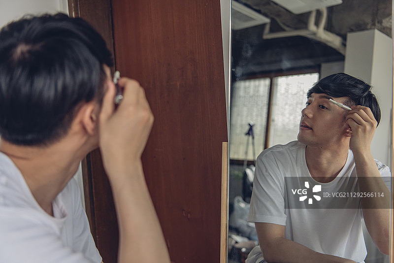 男人用眉刀对着镜子修眉的摄影图片素材