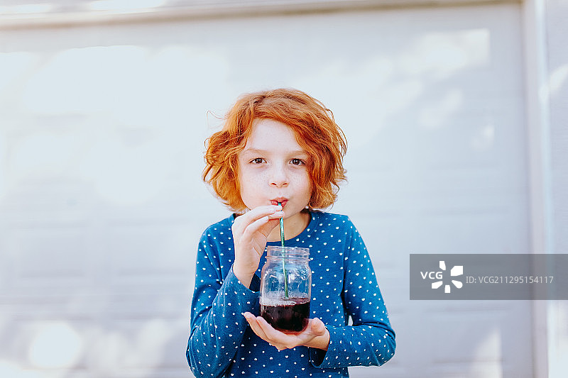 加拿大维多利亚，小男孩靠墙站着喝环保玻璃杯里的水图片素材