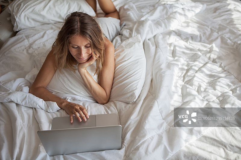 一个女人在床上用笔记本电脑工作图片素材
