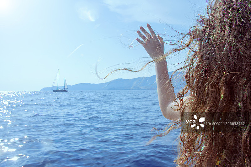 一名年轻女子在帆船前挥手，圣圣维多利亚，意大利图片素材