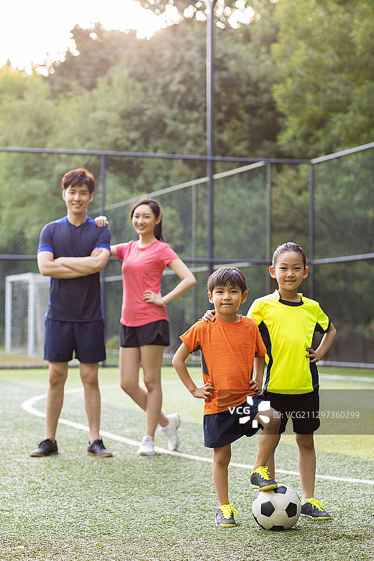 快乐的年轻家庭在足球场踢足球图片素材