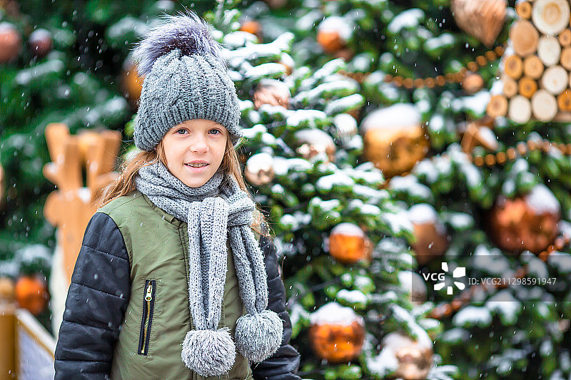 微笑的女孩站在圣诞树旁的肖像图片素材