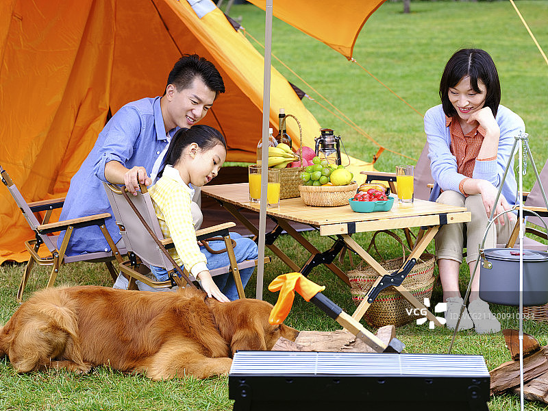 快乐的三口之家和宠物狗在户外露营图片素材