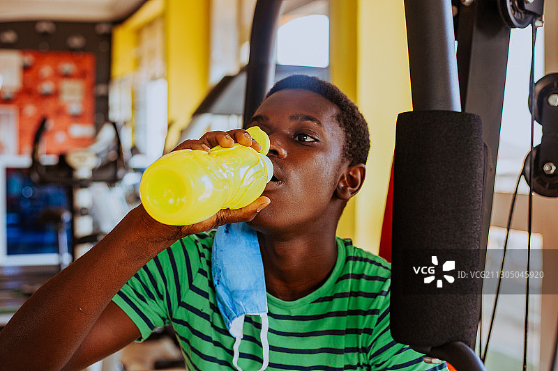 健康和活跃的十几岁的黑人男孩戴着口罩在运动中休息喝水，特马，加纳图片素材