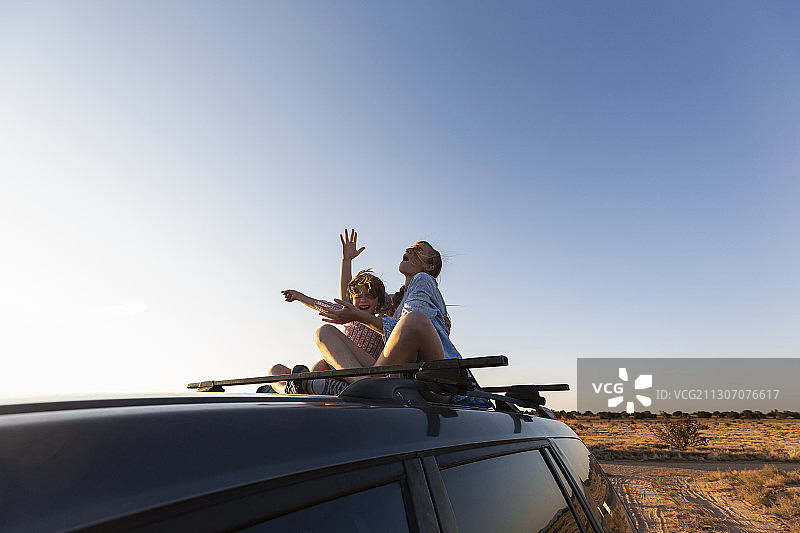 十几岁的女孩和她的弟弟在一辆SUV上行驶在沙漠路上，加利斯特盆地，圣塔菲，新墨西哥州。图片素材