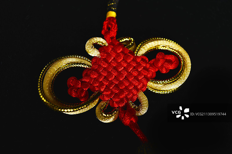 黑色背景下红色金色线绳编织绳艺中国结图片素材