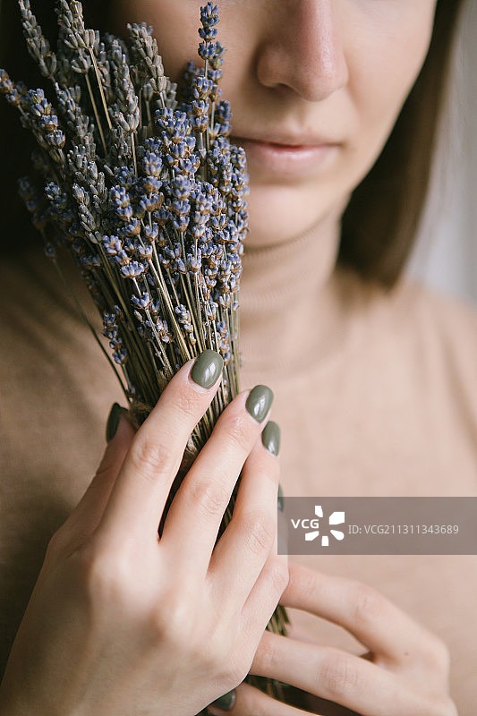 一名年轻女子手持一束薰衣草，靠近她的脸，俄罗斯图片素材