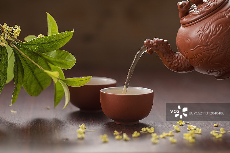 中国茶壶正在倒桂花茶到茶杯中图片素材
