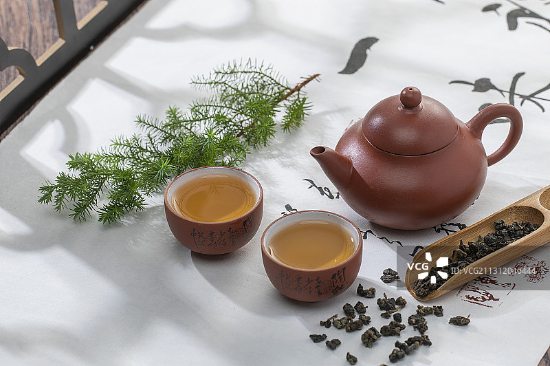 光影下窗花旁的中国茶壶和茶杯及茶则和茶叶图片素材