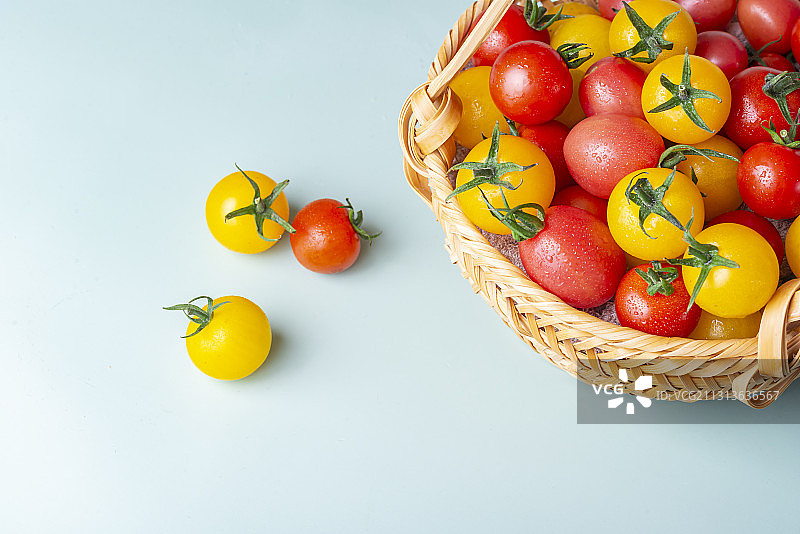 青底桌面上的一篮子红黄双色小西红柿图片素材
