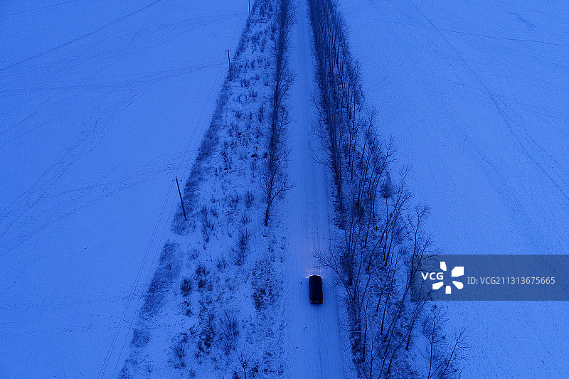 呼伦贝尔一辆汽车行驶在雪夜道路上图片素材