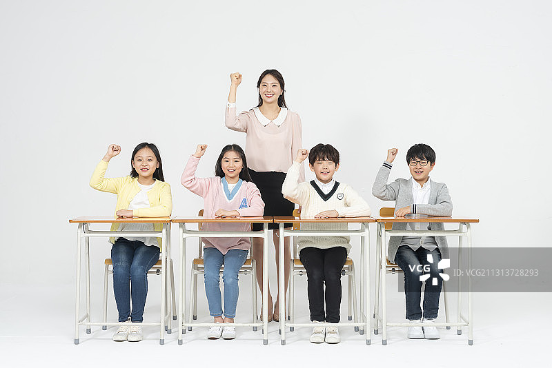老师站在后面，四个孩子坐在桌子旁举手图片素材