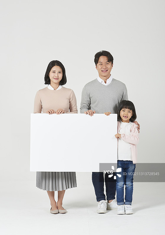 三名家庭成员手持白色空白横幅站在白色背景上图片素材