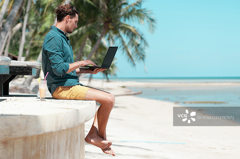 一名男子在泰国科帕颜海滩上使用笔记本电脑图片素材