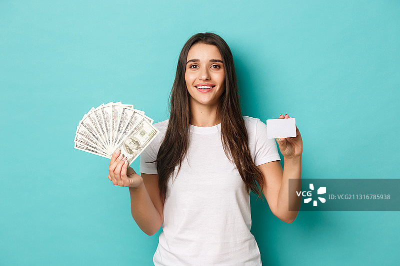 一个微笑的年轻女子的肖像拿着纸币对蓝色的背景图片素材