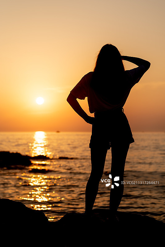 克罗地亚罗温吉，日落时分，一名女子站在海滩上的剪影图片素材
