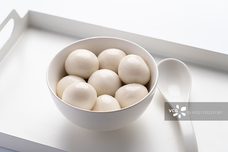 大理石白色纯色背景亮调桌子上一碗煮熟的汤圆图片素材