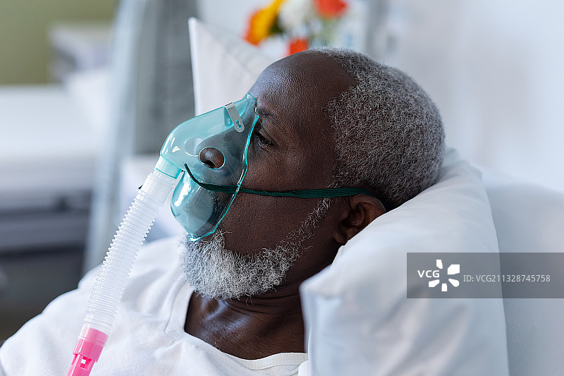 非裔美国男性病人，戴着氧气面罩呼吸机躺在医院病床上图片素材