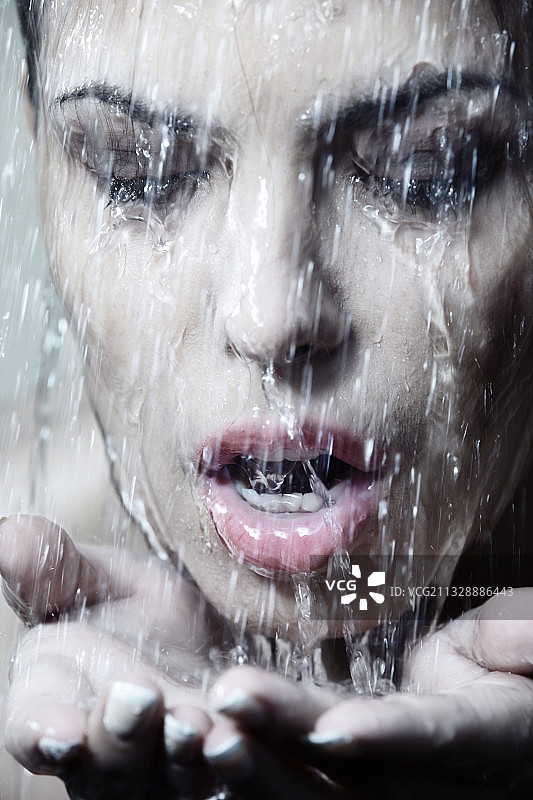 一个女人的肖像，穿着防水的化妆品，水在她的脸上流动图片素材