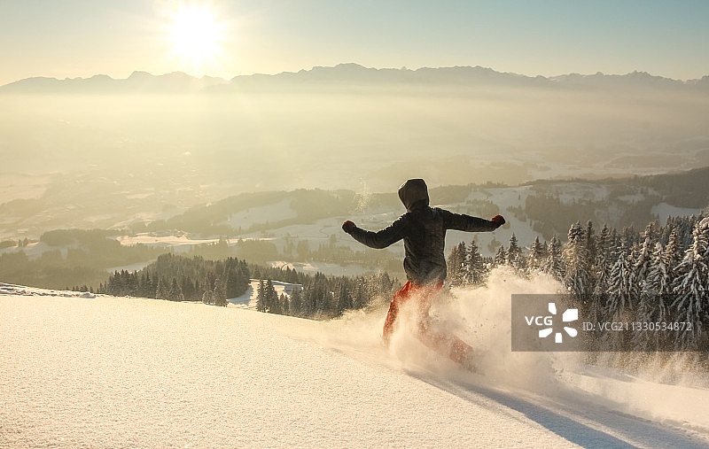 整个长度的女子滑雪板在雪上覆盖的景观对天空在日落图片素材