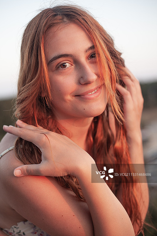 保加利亚西尼莫雷特，日落时微笑的年轻女子手挽头发的肖像图片素材