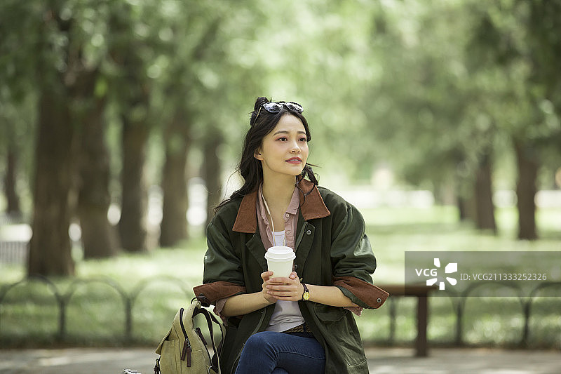 青年女子在城市公园喝咖啡放松休息图片素材