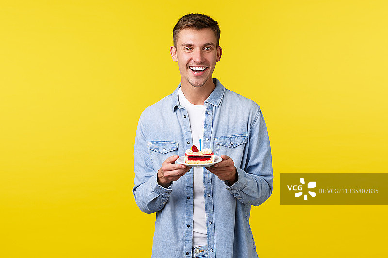 一个微笑的年轻人拿着食物，站在黄色的背景下图片素材