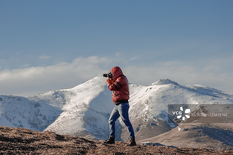 一个年轻人在山上对着天空拍照图片素材