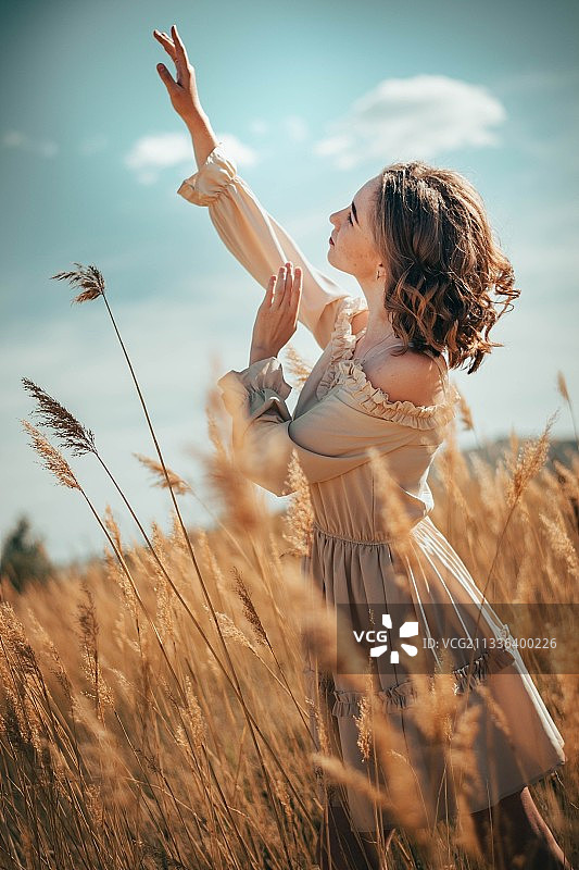 年轻女子在麦田里享受大自然中的日落图片素材