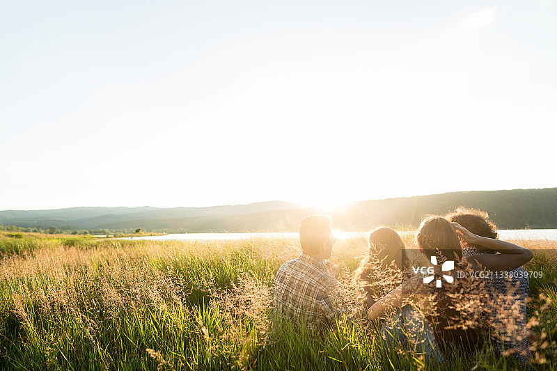 朋友们在夏天一起坐在湖边欣赏日落和傍晚的心情图片素材