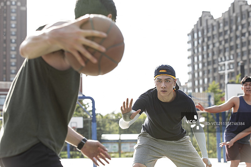 三个青年男子在学校篮球场打篮球图片素材