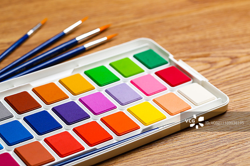 水彩画颜料盒和画笔套装放在木纹桌面背景上图片素材