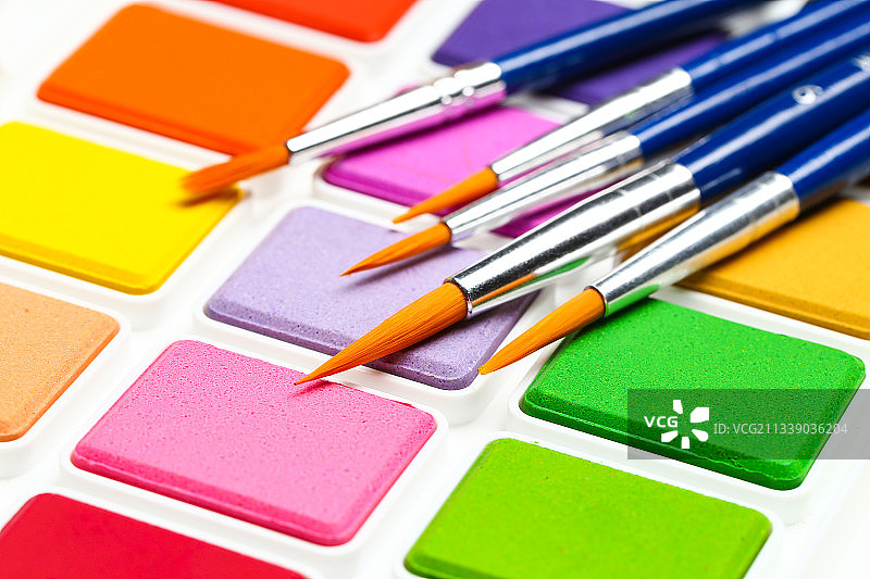 水彩画颜料盒和画笔套装放在木纹桌面背景上图片素材