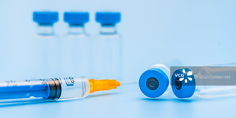 蓝色背景下的疫苗瓶和注射器图片素材