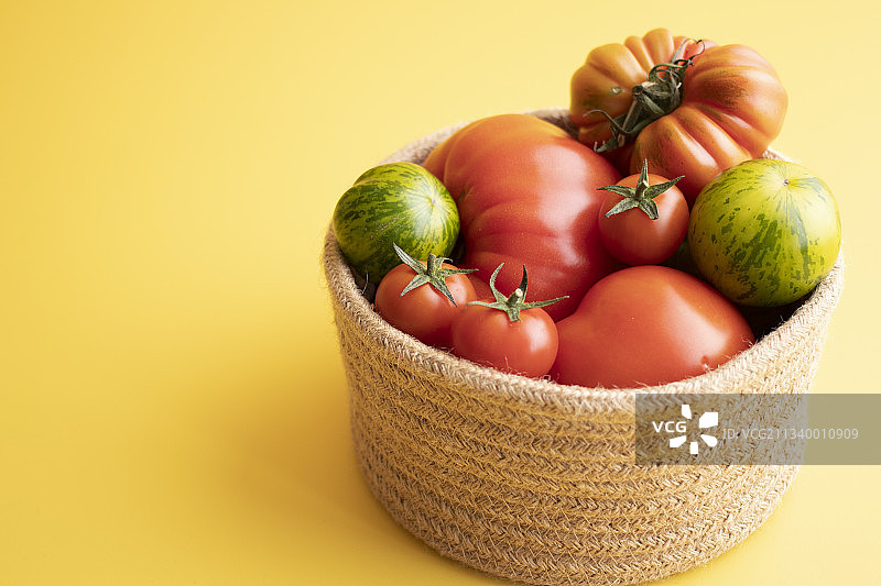 在黄色背景下，篮子里的西红柿的特写图片素材