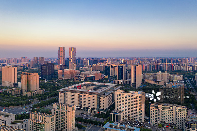 河南郑州绿地中心双子塔与城市天际线夏季日落时户外风光航拍视角图片素材