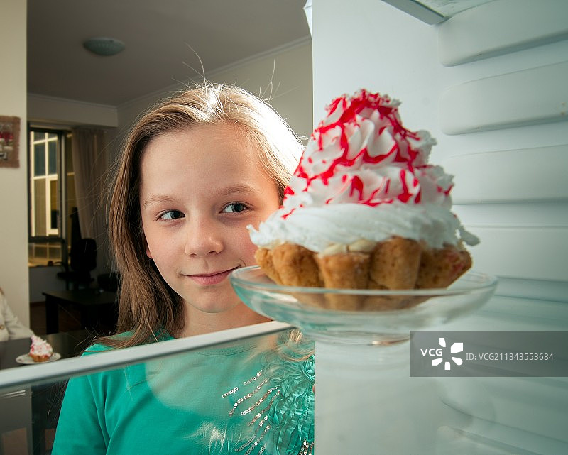 女孩看到冰箱里的甜蛋糕图片素材