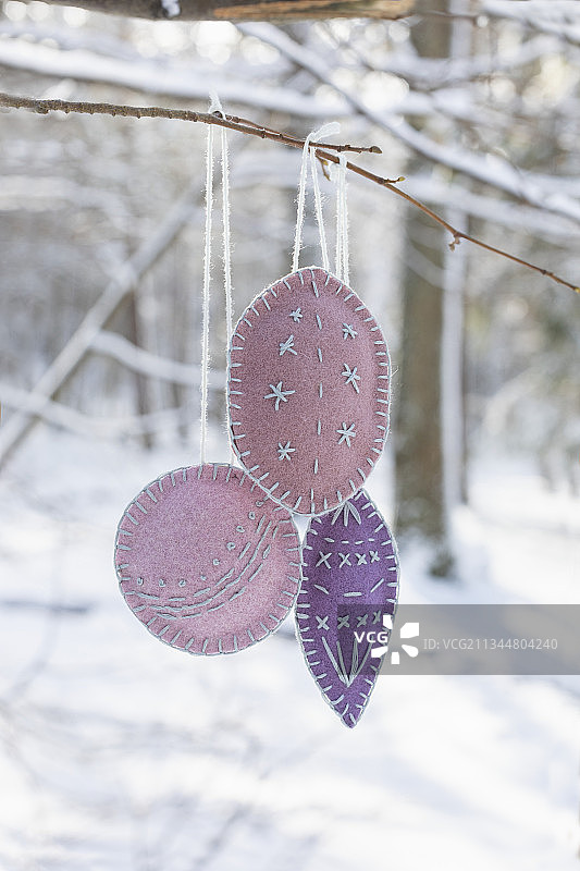 在白雪覆盖的花园里，树枝上悬挂着手工刺绣的毡饰图片素材