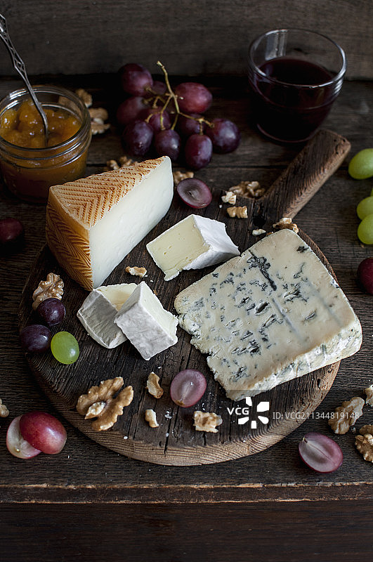 奶酪板配葡萄、核桃、杏酱和一杯红酒(曼契格、布里和蓝奶酪)图片素材