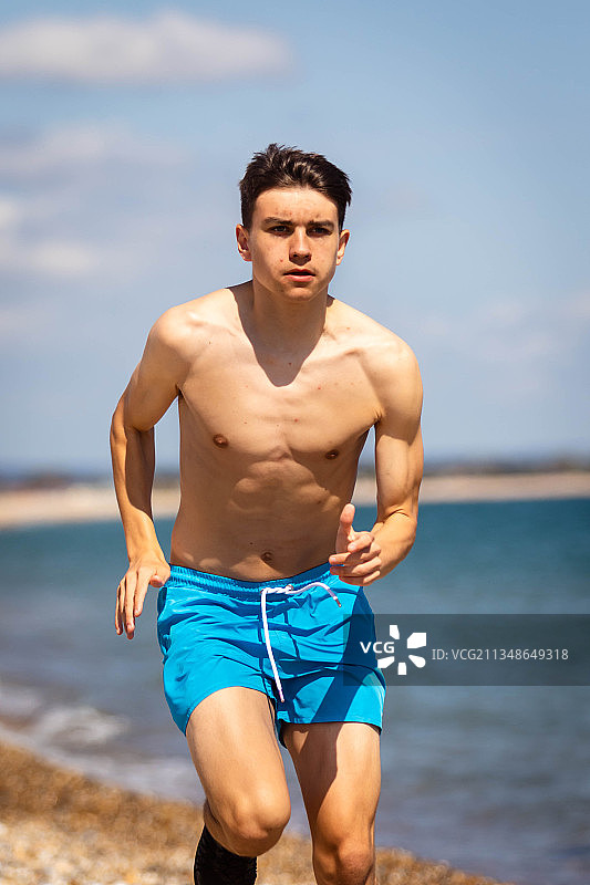 英国西苏塞克斯郡，赤膊青年男子的肖像在海滩上奔跑图片素材