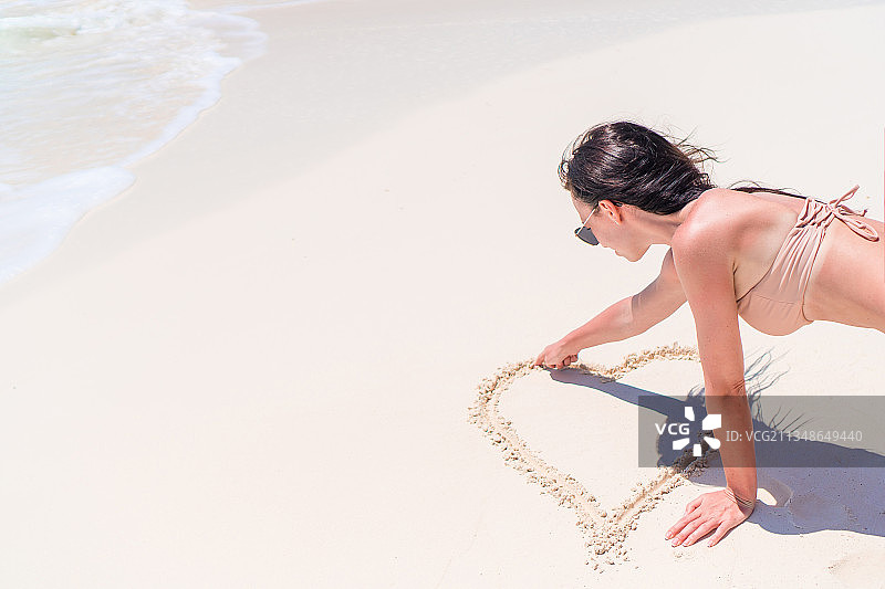 在沙滩上做心形的女人图片素材