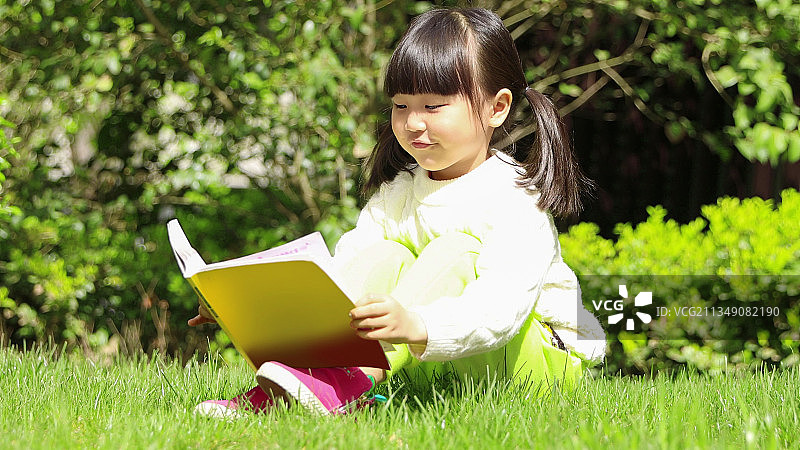 户外草地上看书的小女孩图片素材
