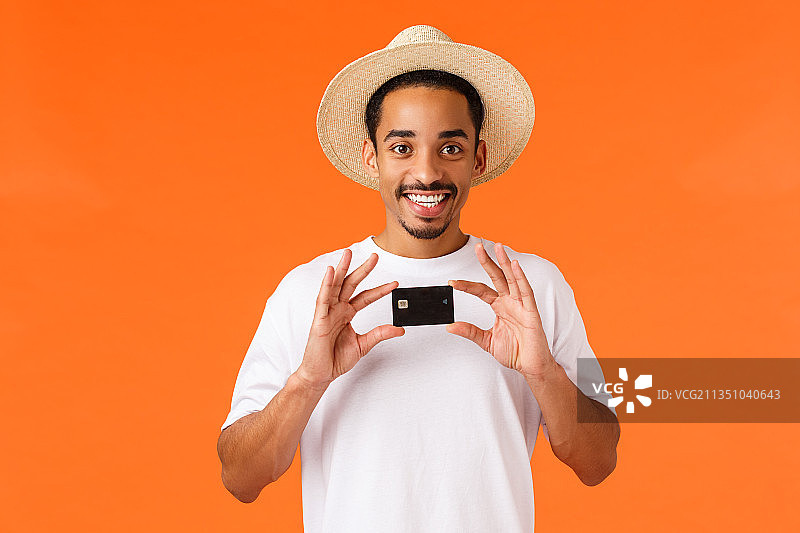 一名微笑的男子手持空白卡片，站在橙色背景下图片素材